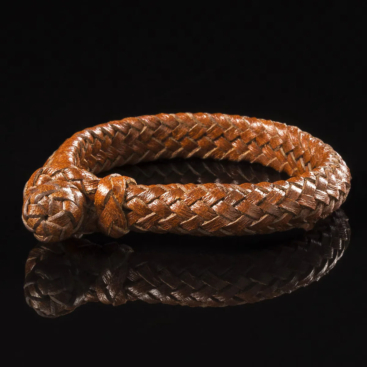 Shiny reddish brown 16-strand braided calfskin leather bracelet with knotted fastening against a black background