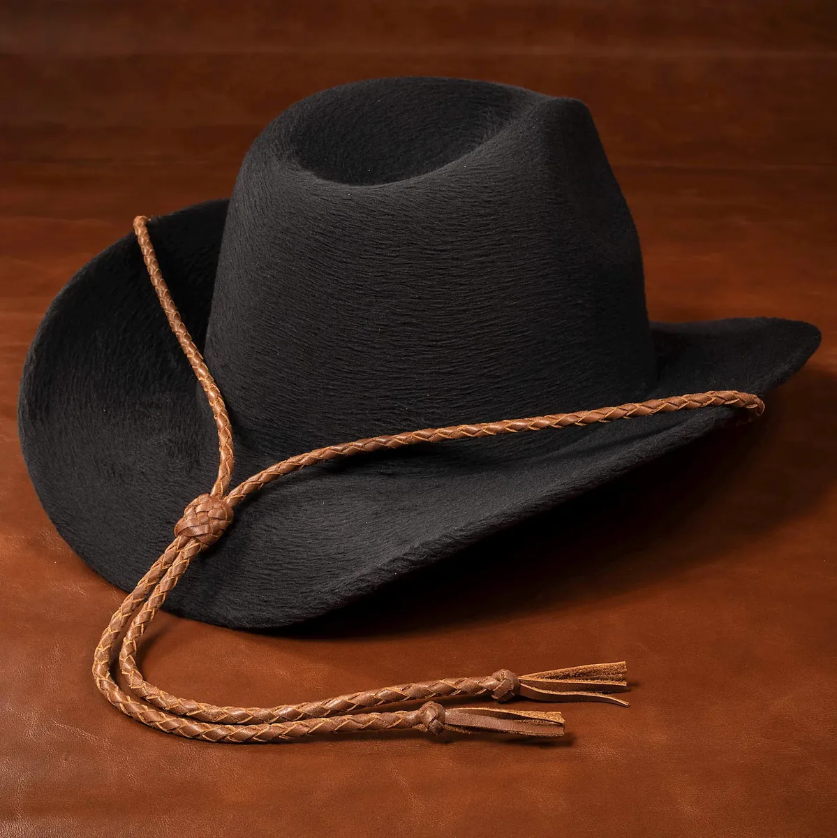 Whiskey-colored hand-braided leather stampede string displayed on a cowboy hat