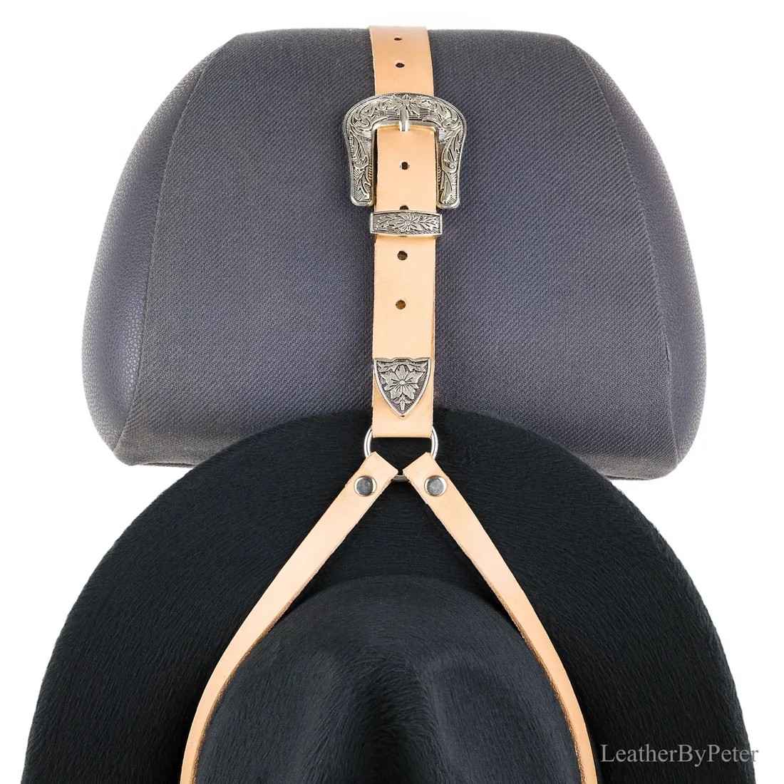 Leather cowboy hat hanger with decorative silver Western buckle fitted to a car seat headrest and holding a black cowboy hat